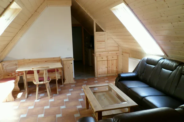 Schwarzes Sofa, Couchtisch und hölzerne Eckbank mit Esstisch unter dem Dachfenster einer Ferienwohnung – Fotoarchiv 2013.