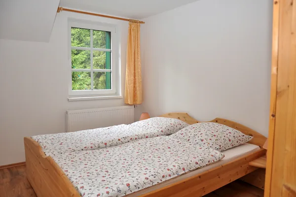 Helles Schlafzimmer mit Doppelbett und Fenster zum Grün.