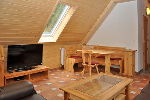 Wohn- und Essbereich mit Holzdecke, Dachfenster, Tisch und Sofa.