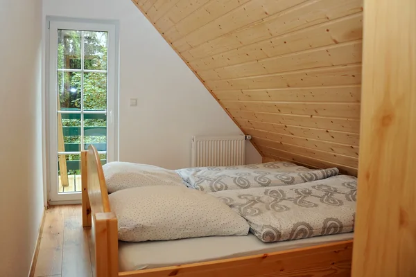 Doppelbett in einem holzverkleideten Schlafzimmer mit Tür nach draußen.