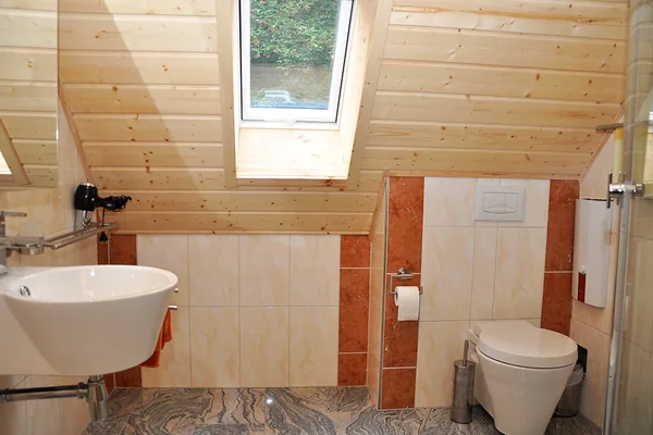 Bad unter einer Dachschräge mit Dachfenster, Waschbecken und WC.