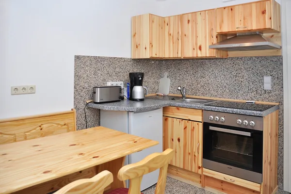 Küche mit Holzfronten, Herd, Spüle und Esstisch.