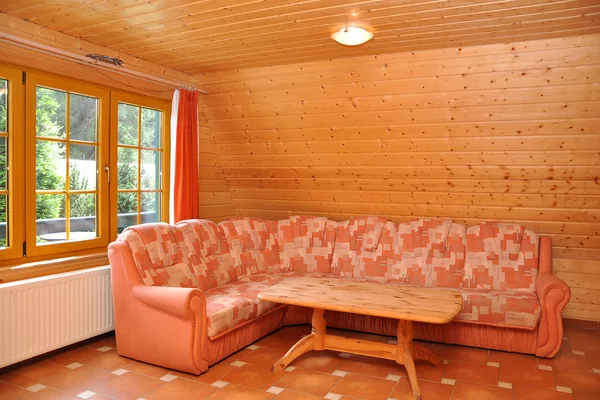 Wohnzimmer einer Finnhütte mit Sofa, Couchtisch und holzverkleideten Wänden.