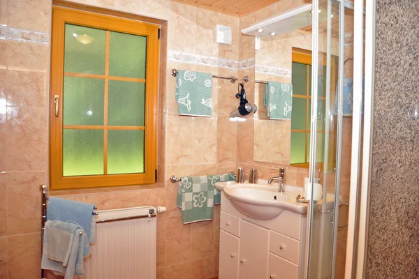Bad einer Finnhütte mit Dusche, Waschbecken und Spiegel.