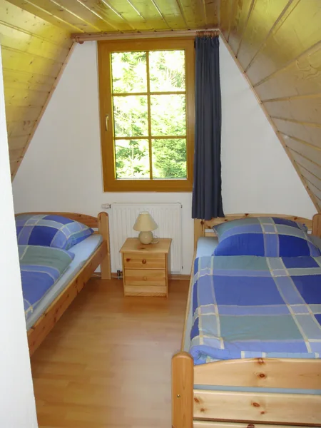 Zwei Einzelbetten mit blau gemusterter Bettwäsche unter dem steilen Holzdach einer Finnhütte – Fotoarchiv 2008.